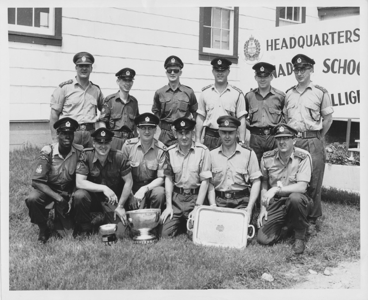 Group photo of twelve men in uniform posing with a trophy. Samuel Gaskin is in front row on left side. 