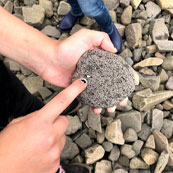 Image of a hand pointing at a rock.