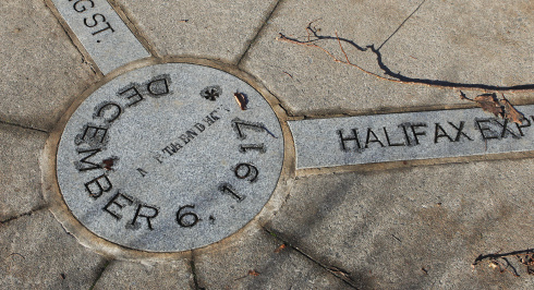 Close-up of a memorial stone in a sidewalk, marking the site of the Halifax Explosion. The inscription highlights the date, December 6, 1917, and its connection to the Halifax Explosion.
