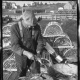 A man on a wharf scaling fish.