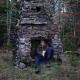 Steve Skafte sitting in a stone fireplace in the woods.