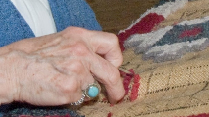 A close up of hands rug hooking