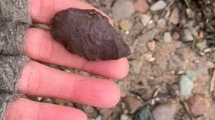 A hand holding an an artifact on a beach.