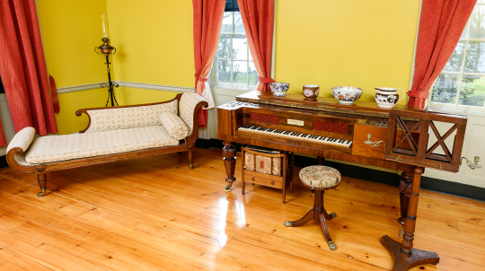 Piano and lounge chair inside a yellow room