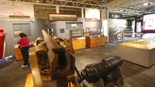Visitors exploring the Navy Gallery, cannon in the foreground.