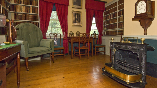 Uniacke Estate library, shelves of books, red curtains and a large green chair.