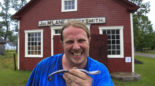 Male costumed interpreter holding a spoon