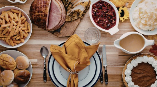 Table set with a harvest feast of ham dinner and sides.